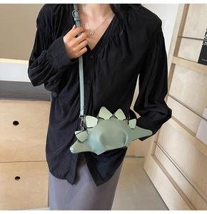 Detail of mint green dinosaur crossbody bag showing PU leather texture and metal strap buckle