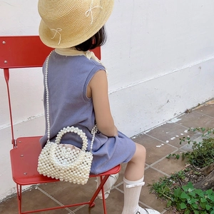 Girl's white pearl beaded crossbody bag with handle shown in lifestyle setting