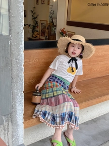 Kindermodeset mit weißem T-Shirt, kariertem Rock und brauner runder Ledertasche