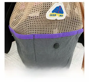Detail of grey nylon beach bag with beige mesh pocket, purple trim and metal snap button