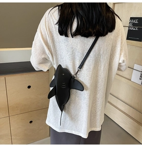 Détail du sac à bandoulière en forme de requin porté par un mannequin avec une fine sangle