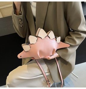 Close-up of pink dinosaur shoulder bag with cream accents and matte leather texture