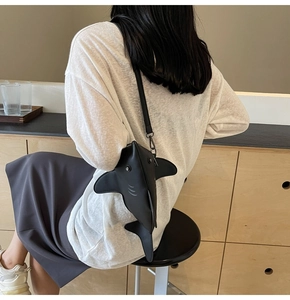 Vue détaillée du sac bandoulière noir en forme de requin porté par un mannequin en café