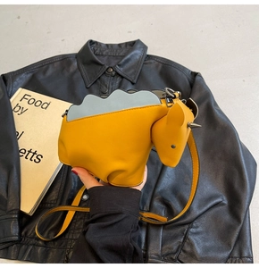 Détail du sac bandoulière jaune en forme de poney avec rivets argentés et bordure ondulée bleue