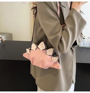 Detail of pink cartoon dinosaur crossbody bag showing PU leather texture and yellow fins