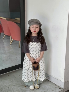 Mädchen-Outfit mit weißem Volantkleid und brauner Mini-Zylindertasche mit goldener Kette