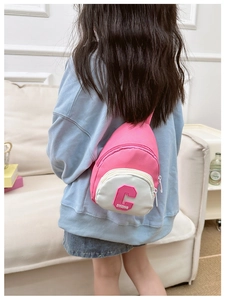 Rear view of a pink kids chest bag with C letter embroidery on a model at home