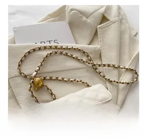 Detail of white quilted crossbody bag with golden chain and adjustable metal ball buckle