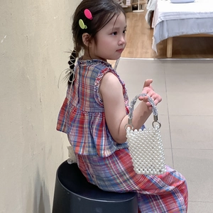 Girl carrying white pearl beaded handbag with silver metal handle in plaid outfit