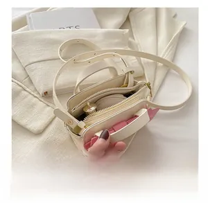 Detail view of mini off-white crossbody bag interior with zipper and pink accent