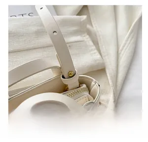 Detail of cream kids handbag with pink bow decoration and gold metal zipper closure