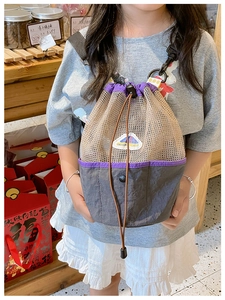 Close-up of kids mesh drawstring bucket bag with beige nylon net and purple trim details
