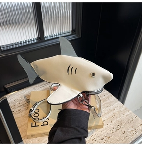 Détail de la fermeture éclair argentée sur le sac bandoulière crème en forme de requin