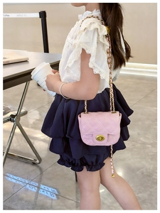 Pink quilted crossbody mini bag for kids with golden chain strap shown on a young model