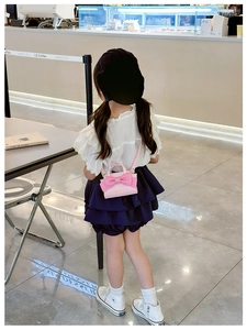 Detail of pink mini crossbody bag with a large bow shown on a child model's shoulder