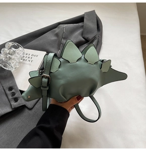 Detail view of a cute dinosaur-shaped crossbody bag in mint green with realistic back fins
