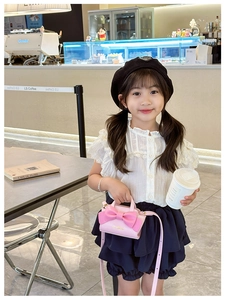Pink bow mini shoulder bag styled with a children's summer outfit in a cafe setting