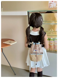 Back view of a child wearing a mesh drawstring shoulder bag in a cozy cafe setting