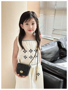 Girl wearing a minimalist white embroidered dress with a black quilted chain shoulder bag