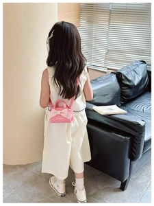 Rear view of a child wearing a pink mini crossbody bag with a large decorative bow