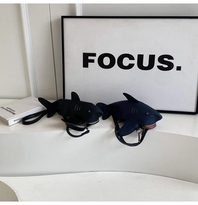 Détail des sacs bandoulière en forme de requin en similicuir noir et bleu sur support blanc
