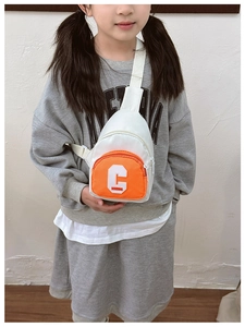 Detail of kids chest bag with orange contrast pocket and chenille letter C embroidery