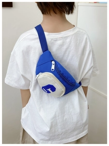Detail view of the contrasting blue and white kids chest bag with letter C and strap
