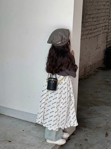 Detail einer Mini-Zylindertasche in Schwarz mit goldener Kette auf Kinderoutfit