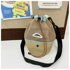 Detail of drawstring mesh beach bag with mountain patch and blue trim on khaki canvas