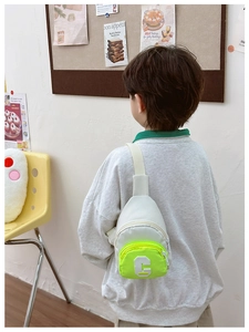 Detail of kids chest bag with green neon pocket and white towel embroidered C letter