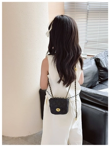 Rear view of child wearing black quilted leather mini crossbody bag with gold chain strap