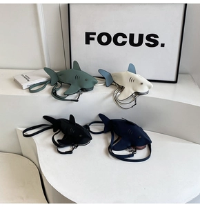 Quatre sacs à bandoulière en forme de requin sur des podiums blancs épurés