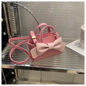 Detailed macro view of pink leather mini handbag with oversized bow and golden hardware