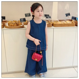 Girl wearing blue denim vest and trousers with a stylish red quilted chain handbag