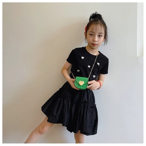 Detail of green heart-shaped crossbody bag with gold chain strap on child's outfit