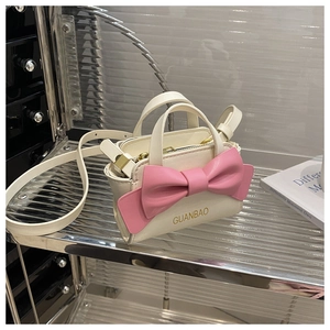 Detail of a mini crossbody bag with a large pink 3D bow and GUANBAO brand logo