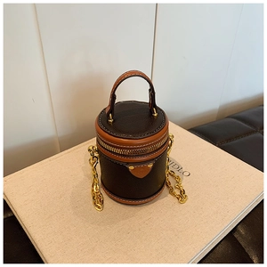 Detailansicht einer Mini-Zylindertasche aus zweifarbigem Leder mit goldener Kette