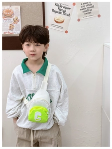 Detail of white and lime green kids chest bag with letter C embroidery on model