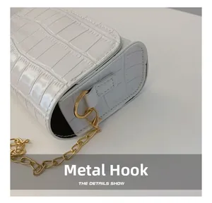 Detailed close-up of white crocodile pattern texture with golden metal chain hook