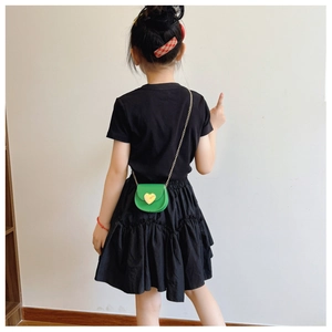 Rear view of a child wearing a green heart-shaped mini crossbody bag with a gold chain