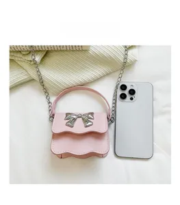 Mini pink bow crossbody bag shown next to a smartphone to demonstrate the small size