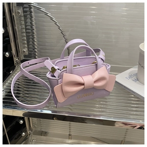 Detailed close-up of lavender leather mini bag with a pink bow and golden logo