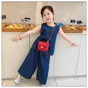 Detail of red quilted mini chain bag paired with dark blue denim outfit for kids