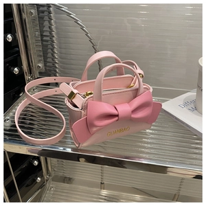 Detailed view of pink mini crossbody bag featuring a 3D bow decoration and handle