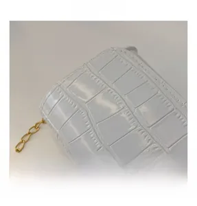 Macro shot of white crocodile embossed texture and metallic chain on child bag