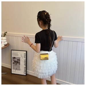 Girl's crossbody bag with crocodile texture and gold chain strap on stylish summer outfit