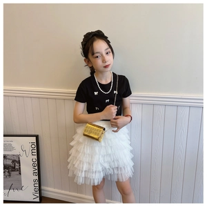 Detail of a girl wearing a black bow t-shirt and white mesh skirt with a gold chain bag