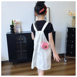 Detail of pink heart crossbody bag with gold buckle and chain strap on a child