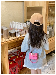 Pink mini crossbody bag with silver bow clasp and chain shown on child in shop