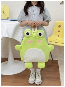 Detail of green frog school bag with big eyes shown on a child in a home setting
